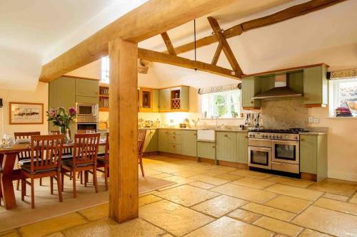 奇平卡姆登Groves Barn at Norton Grounds的厨房配有绿色橱柜和桌椅