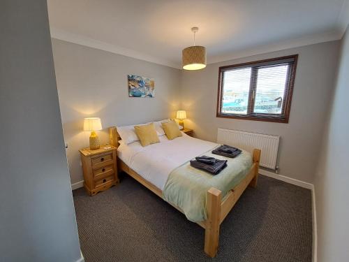 BrundallRiver Retreat - Norfolk Broads的一间卧室配有一张床、两盏灯和一个窗户。
