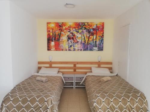 阿拉德Desert Sunrise Arad的一间卧室设有两张床,墙上挂着一幅画