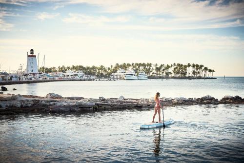 马拉松Courtyard by Marriott Faro Blanco Resort的站在水中桨板上的比基尼妇女