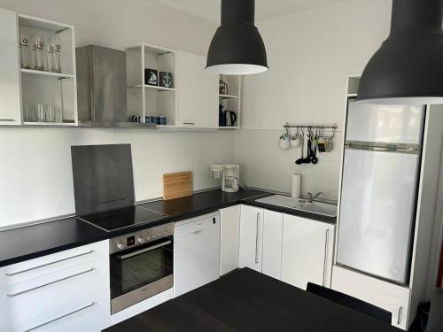 费马恩Insel Hus的厨房配有白色橱柜和黑色台面