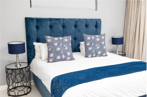 约翰内斯堡One Hyde Park Apartments Sandton的一张带蓝色床头板和枕头的床