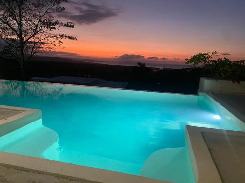 里奥圣胡安Piscina vista al mar, Jacuzzi con agua caliente的蓝色的游泳池,背景是日落