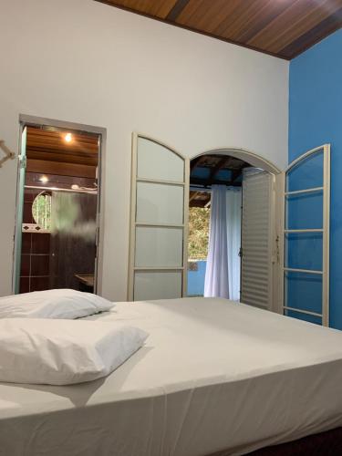 若阿诺波利斯Pousada camping Recanto Joanópolis的卧室设有一张白色大床和一扇窗户。