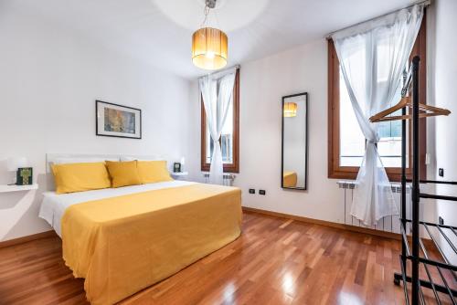 威尼斯The Most Central In Venice [ San Marco Rialto ]的一间卧室配有一张带黄色床单和木地板的床。