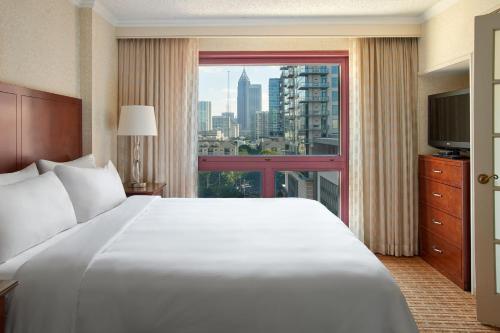 亚特兰大Atlanta Marriott Suites Midtown的卧室设有一张白色大床和大窗户