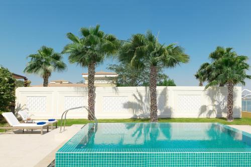 阿布扎比阿布扎比（大运河）丽思卡尔顿酒店的一座拥有棕榈树和白色围栏的游泳池