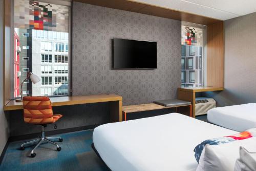 明尼阿波利斯Aloft Minneapolis的酒店客房设有一张床、一张书桌和一台电视机。