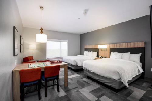 休斯顿TownePlace Suites by Marriott Houston Hobby Airport的酒店客房带两张床和一张桌子以及椅子。