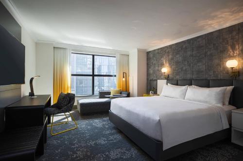 纽约Renaissance New York Times Square Hotel by Marriott的酒店客房配有一张床、一张桌子和一把椅子。