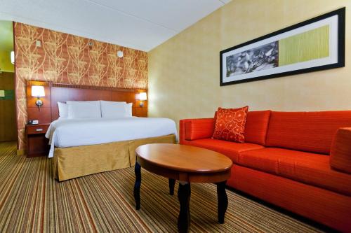 德斯普兰斯芝加哥奥黑尔万怡酒店的酒店客房,配有一张床和一张红色的沙发
