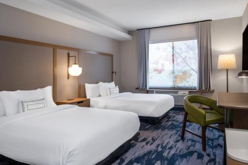 布鲁克林中心Fairfield Inn & Suites Minneapolis North的酒店客房,配有两张床和椅子