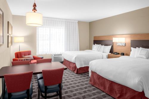 费尔菲尔德TownePlace Suites Cincinnati Fairfield的酒店客房带两张床和一张桌子以及椅子。