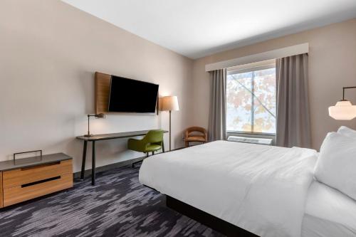 桑达斯基Fairfield by Marriott Inn & Suites Sandusky的酒店客房配有一张床、一张书桌和一台电视。