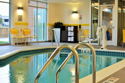 奥马哈奥马哈西北万豪费尔菲尔德酒店的一座游泳池,里面设有黄色的椅子和桌子