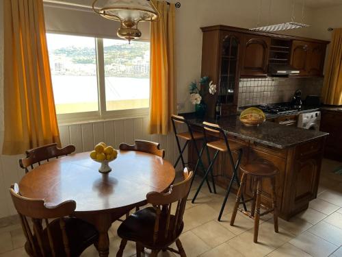 圣保罗湾城Groundfloor Apartment By The Sea, Fabulous Views的厨房配有带椅子的木桌和厨房岛。