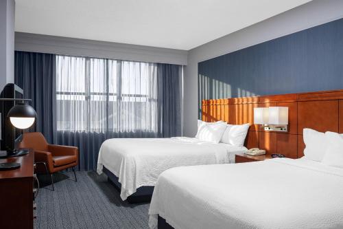 朗康科马长岛麦克阿瑟机场万怡酒店的酒店客房设有两张床和窗户。