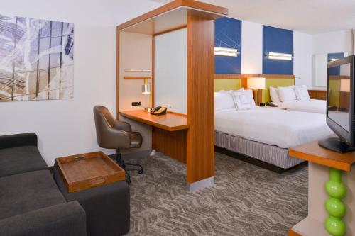 达拉姆春季山丘套房达勒姆教堂山酒店的酒店客房设有两张床、一张桌子和一张沙发。