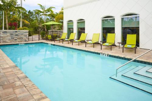 埃斯特罗SpringHill Suites by Marriott Fort Myers Estero的一座带黄色椅子的游泳池和一座建筑