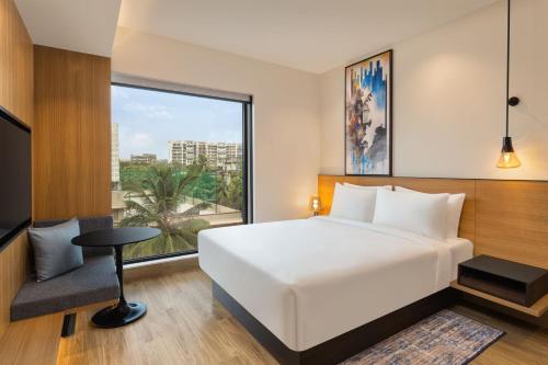 孟买Fairfield by Marriott Mumbai International Airport的卧室设有白色的床和大窗户