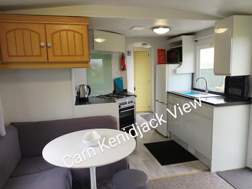 彭赞斯Carn Kenidjack View Caravan, space, peace and tranquillity的小厨房配有桌子和白色桌子