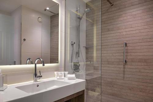 曼彻斯特AC Hotel by Marriott Manchester City Centre的一间带水槽和玻璃淋浴的浴室