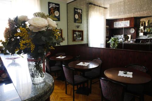 博洛尼亚艾尔伯格加里胜大酒店的一间设有两张桌子和花瓶的餐厅