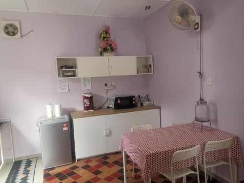 彭亨Haji Homestay - A tiny house with 2 bedrooms的厨房配有桌子、带桌子的柜台和冰箱。