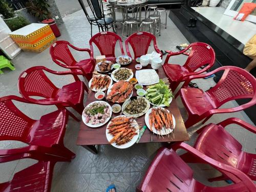 隆海Nguyễn Kim Motel的一张桌子,上面放着食物盘,上面放着红色椅子