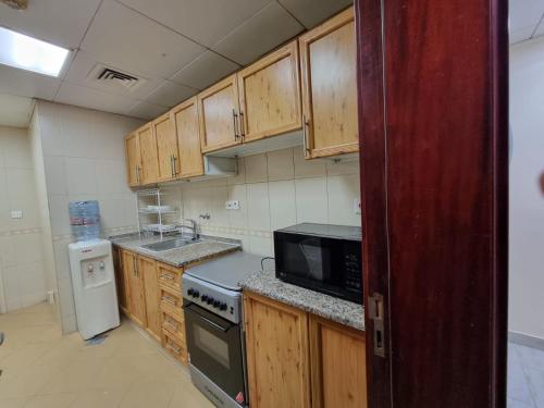 阿布扎比MBZ - Cosy Separate Room in Unique Flat的厨房配有木制橱柜和黑微波炉