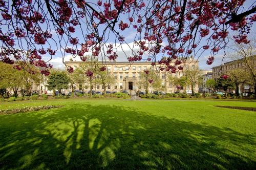 格拉斯哥Kimpton Blythswood Square Hotel & Spa, an IHG Hotel的一座大建筑,拥有绿意盎然的草坪和树