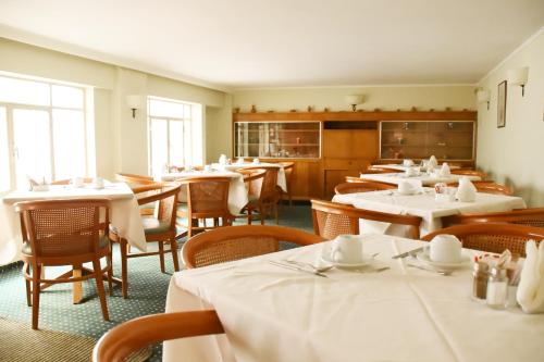 雅典阿德里安酒店的用餐室配有桌椅和白色桌布