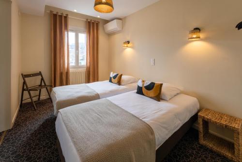 阿普特L'Aptois Hôtel的酒店客房设有两张床和窗户。