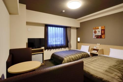 石卷市石卷中央路线酒店的酒店客房设有两张床和一张桌子。