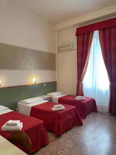 维亚雷焦卢卡斯酒店的配有红色窗帘的客房内的两张床