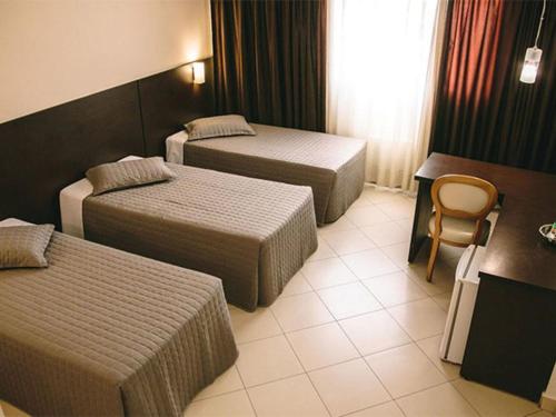 库里提巴Hotel Dunamys Curitiba的酒店客房,配有两张床和椅子
