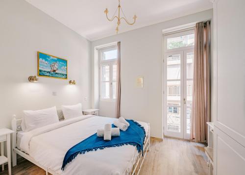 雅典Neapolis 1897 Boutique Luxury Rooms的白色卧室配有蓝色调的大床