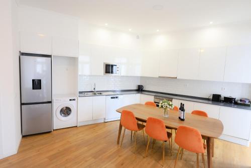 里斯本Lisboa Intendente 3Bedroom Apartment with Balcony的厨房配有木桌和橙色椅子