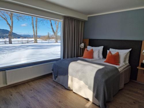 GranGranavolden Hotel & Gjæstgiveri的一间卧室配有带橙色枕头的床和大窗户