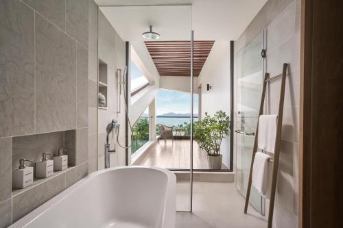 芽庄Boma Resort Nha Trang的带浴缸的浴室和大窗户