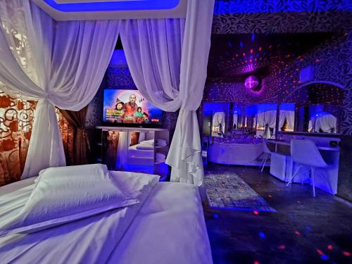 布拉索夫Hotel Boutique Mikaela (Adult Only)的一间卧室配有一张床,酒吧配有紫色灯
