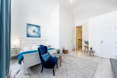 科希策Center Apartment Mlynska Kosice with private Parking的白色卧室配有床和蓝椅