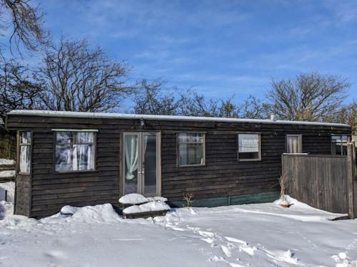 雷克瑟姆Ferny Roost Cabin.的雪中带栅栏的小房子