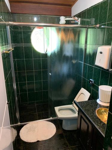 若阿诺波利斯Pousada camping Recanto Joanópolis的绿色瓷砖浴室设有卫生间和淋浴。