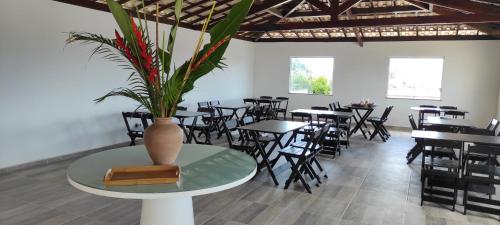伊塔帕里卡岛维拉克鲁兹Pousada Jardins - Mar Grande的配有桌椅和花瓶的餐桌餐厅