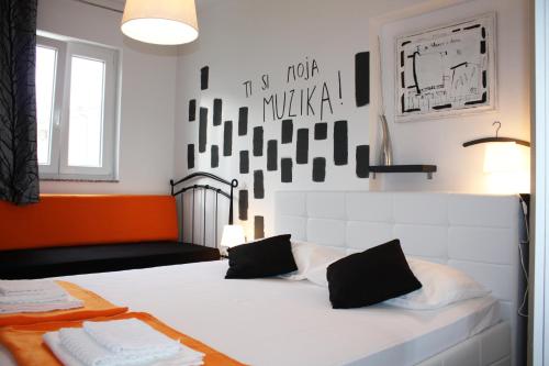 拉布Apartman Maria 1的一间卧室配有一张白色的床,墙壁上装饰着橙色和黑色