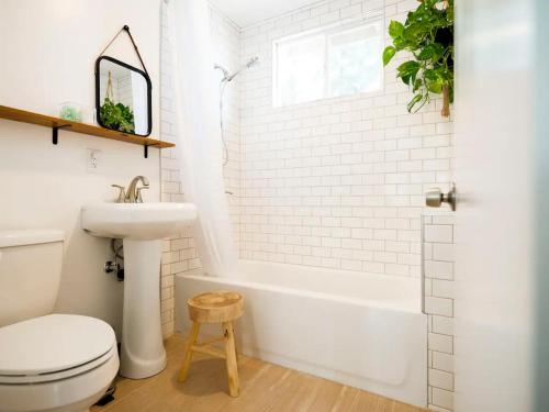 约书亚树The Zen - Outdoor Shower, Gas Fireplace, Walkable to Shops & Restaurants的浴室配有白色浴缸、卫生间和水槽。