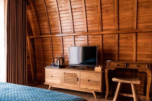 贝都古Kabinku Bali的卧室的木制梳妆台上配有电视
