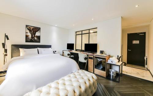 全州市KAMA Hotel的卧室配有一张白色大床和一张书桌