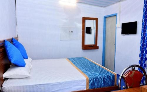 蒙纳Blackcherry Munnar的一间卧室配有一张带蓝色枕头和镜子的床